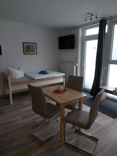 ein Wohnzimmer mit einem Tisch, Stühlen und einem Bett in der Unterkunft City-Pension Senftenberg / Apartment Nr. 3 in Senftenberg