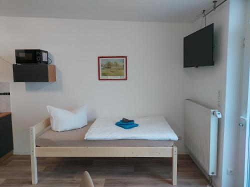 a room with a bed with a tv on the wall at City-Pension Senftenberg / Apartment Nr. 3 in Senftenberg