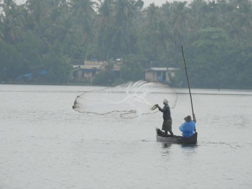 two people in a boat with a net in the water at Lago Leisure Resort & Spa in Cherai Beach