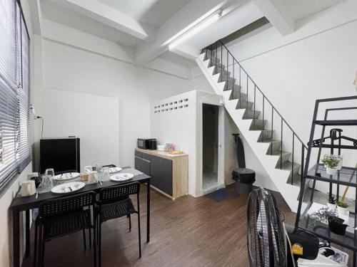 a living room with a table and a staircase at Tolomhouse in Hat Yai
