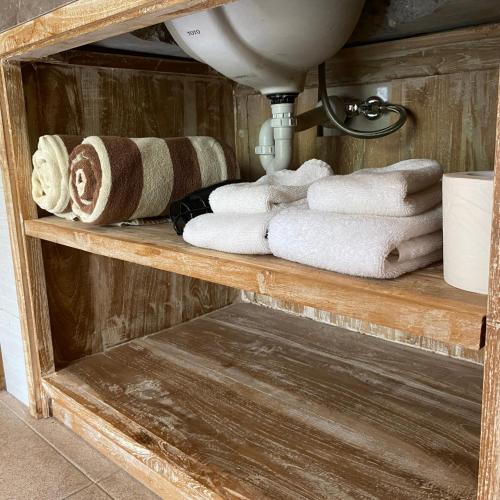 a bathroom shelf with towels and a sink at Green D'mel Bali in Nusa Dua