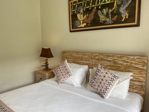 a bedroom with a bed with white sheets and pillows at Green D'mel Bali in Nusa Dua