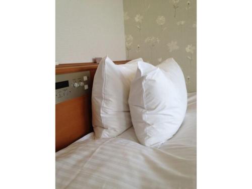 2 almohadas blancas encima de la cama en Tottori City Hotel / Vacation STAY 81349, en Tottori
