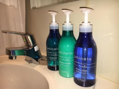 drei Flaschen Reinigungsmittel auf einem Waschbecken in der Unterkunft Tottori City Hotel / Vacation STAY 81351 in Tottori