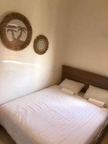 a bed with two pillows and a mirror on the wall at NOMAD Tropical Hostel Canggu in Dalung