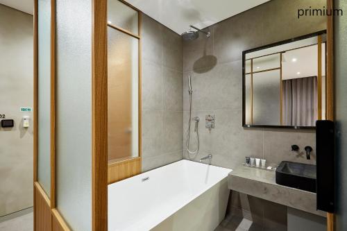 uma casa de banho com uma banheira, um lavatório e um espelho. em Hotel The Artist Yeoksam em Seul