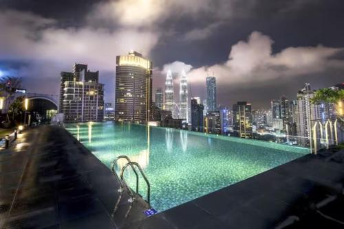 吉隆坡的住宿－Maxhome Cozy at Dorsett Bukit Bintang，一座晚上拥有城市天际线的游泳池