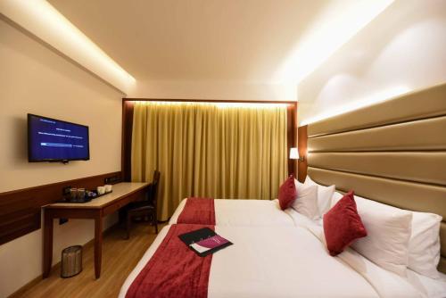 ein Hotelzimmer mit einem Bett, einem Schreibtisch und einem TV in der Unterkunft Ayra Boutique Hotel in Bangalore