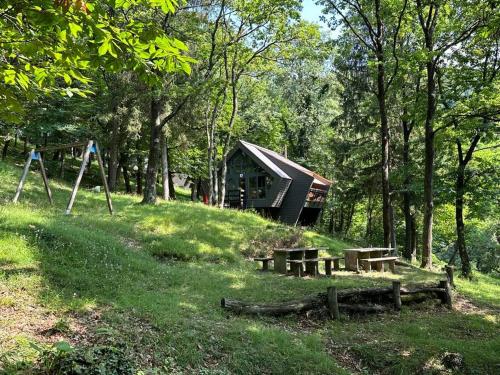 una cabaña en el bosque con bancos y un columpio en Malcantone/Tessin, Bosco della Bella, Casetta 15, en Termine