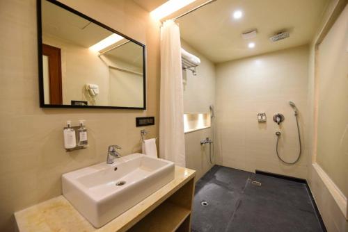 a bathroom with a sink and a mirror and a shower at Ayra Boutique Hotel in Bangalore