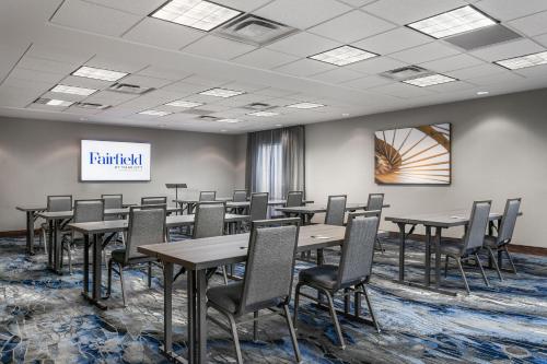 a conference room with tables and chairs and a screen at Fairfield Inn & Suites by Marriott Chattanooga South East Ridge in Chattanooga