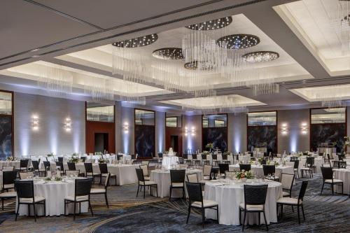 a banquet hall with white tables and chairs and a chandelier at JW Marriott Grand Rapids in Grand Rapids