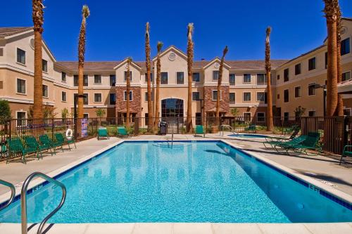 a swimming pool with palm trees and buildings at Staybridge Suites Palmdale by IHG in Palmdale