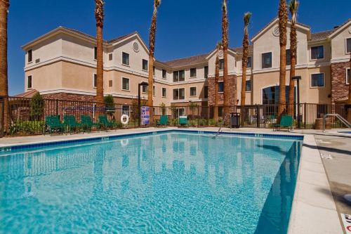 a swimming pool in front of a building with palm trees at Staybridge Suites Palmdale by IHG in Palmdale