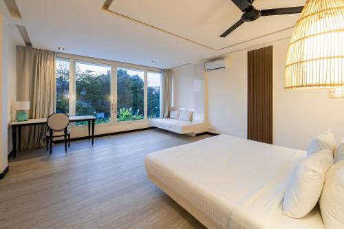 a bedroom with a white bed and a desk and window at Eden The Residence at The Sea Seminyak in Seminyak