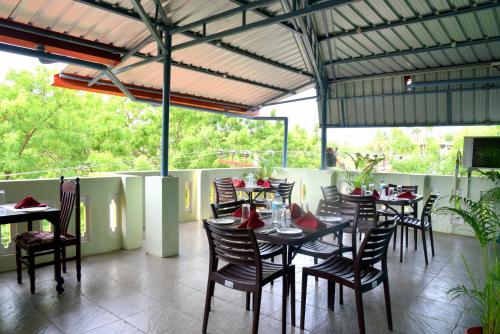 a dining room with tables and chairs and windows at Serenity Sands Beach Resort in Puducherry