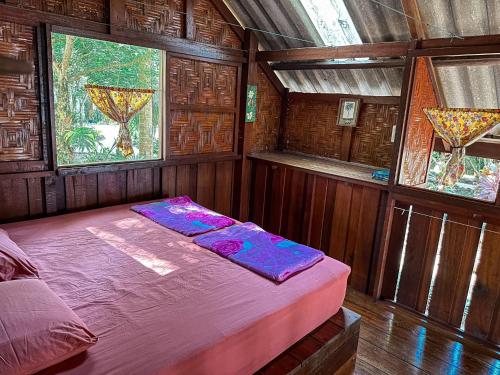 1 dormitorio con 1 cama en una habitación de madera con ventanas en Sawasdee Resort, en Koh Chang