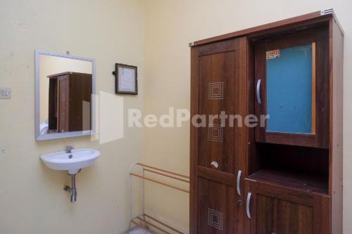 a bathroom with a sink and a wooden cabinet at Hotel Sido Langgeng Tawangmangu Mitra RedDoorz in Karanganyar