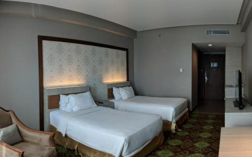 una habitación de hotel con 2 camas y una silla en Five Premiere Hotel, en Samarinda
