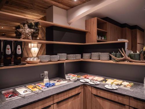 a kitchen with a counter with plates and food at Central Hotel & Apart mit Landhaus Central in Fügen