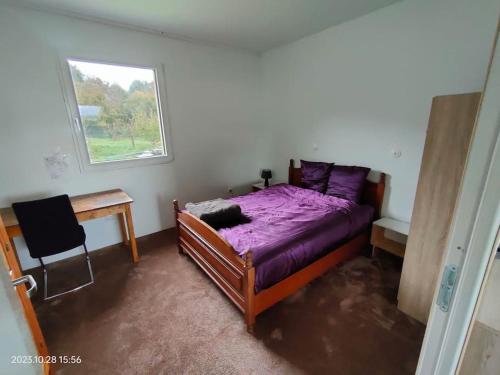 een slaapkamer met een paars bed, een bureau en een raam bij Maison calme à la campagne 