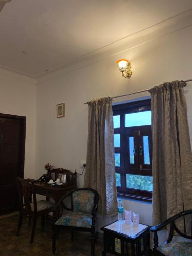 a living room with a table and a window at Dera Padlia - A Rural Experience Farm Stay 