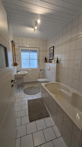 a white bathroom with a tub and a sink at Ferienhaus Dhrontal in Neumagen-Dhron