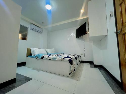 um pequeno quarto com uma cama e uma televisão em Aloha Cabana Resort And Events em Surigao