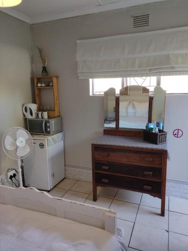 a room with a dresser and a microwave and a refrigerator at Stonehenge Cottage in Oudtshoorn