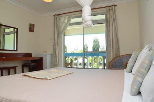 ein Schlafzimmer mit einem weißen Bett und einem Fenster in der Unterkunft ASINS HOLIDAY INN HOTEL in Ukunda