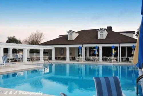 a swimming pool with chairs and a house at Tinsley - Patio Villa In The Village Of Hawkins in The Villages