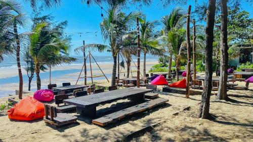 a picnic table on the beach with palm trees at Long Hải Channel Beach Resort in Long Hai