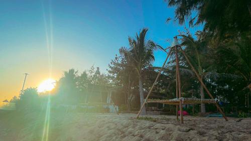 a swing set on a beach with the sun setting at Long Hải Channel Beach Resort in Long Hai