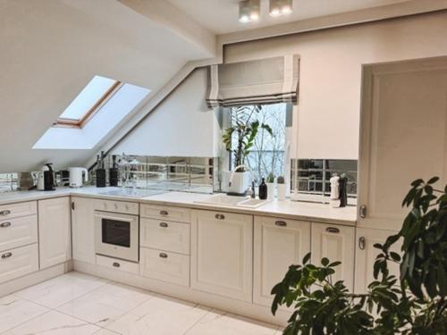 a large kitchen with white cabinets and a window at Apartament Polli in Grudziądz