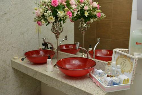 two red sinks in a bathroom with flowers in the mirror at Hotel São Bento in Marabá