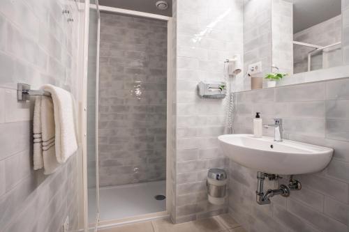 y baño blanco con lavabo y ducha. en harry's XL Hotel, en Salzburgo