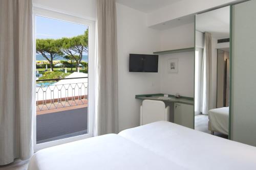 a bedroom with a bed and a window with a view at Hotel Bauer & Sporting in Lido di Jesolo