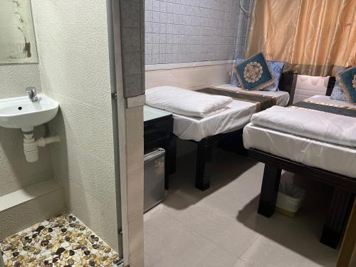 Habitación pequeña con 2 camas y lavamanos en Temple Street Hotel, en Hong Kong