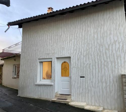 un edificio blanco con puerta y ventana en Maison au coeur de la Dombes, en Le Plantay