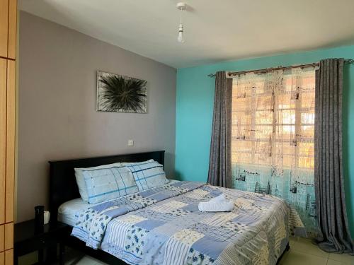 MachakosにあるTrudy homes 1 bedroomの青い壁と窓のあるベッドのある寝室