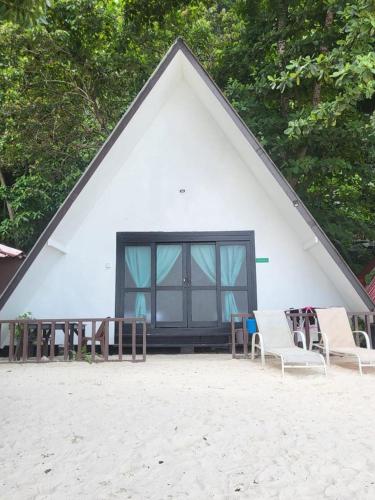 ein dreieckiges Gebäude mit Stühlen und Tischen am Strand in der Unterkunft DEWATI ROOMSTAY B&B in Lang Tengah