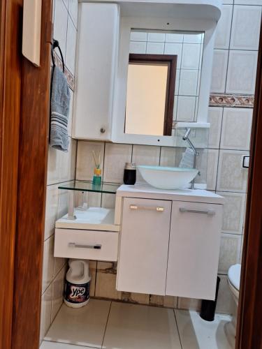 y baño con lavabo blanco y espejo. en Recanto do Sossego, en Guarujá