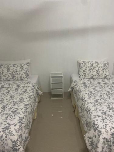 twee bedden in een kleine kamer met een nachtkastje ertussen bij Chu Mon's Homestay Janda Baik (15 min from river) in Bentong