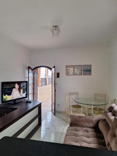 uma sala de estar com um sofá e uma televisão em Recanto do Sossego no Guarujá