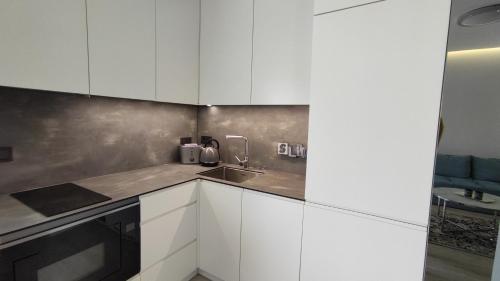 a kitchen with white cabinets and a sink at NEW J&R Apartment near Girstutis, Free private parking & Self Check-In in Kaunas