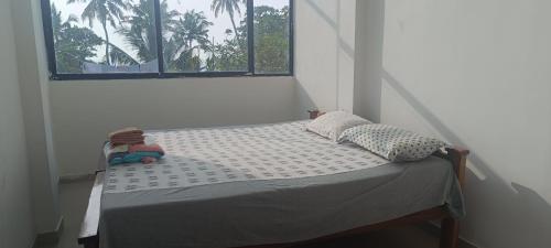 - un petit lit dans une chambre avec fenêtre dans l'établissement Beach vibe hostel, à Alappuzha