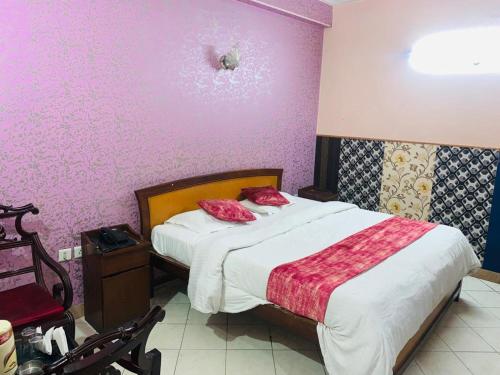 sypialnia z łóżkiem z czerwonymi poduszkami w obiekcie Hotel The New Avenue w mieście Aligarh
