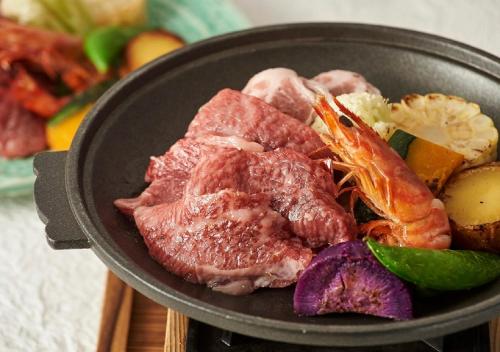 a pan filled with meat and vegetables on a table at Hotel Monterey Okinawa Spa & Resort in Onna