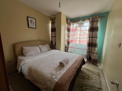 a small bedroom with a bed with a window at Eclectic 2 bedrm homely & comfy in Machakos