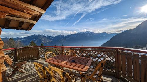 uma mesa de madeira e cadeiras numa varanda com montanhas em Alpenpanorama Ovronnaz em Ovronnaz